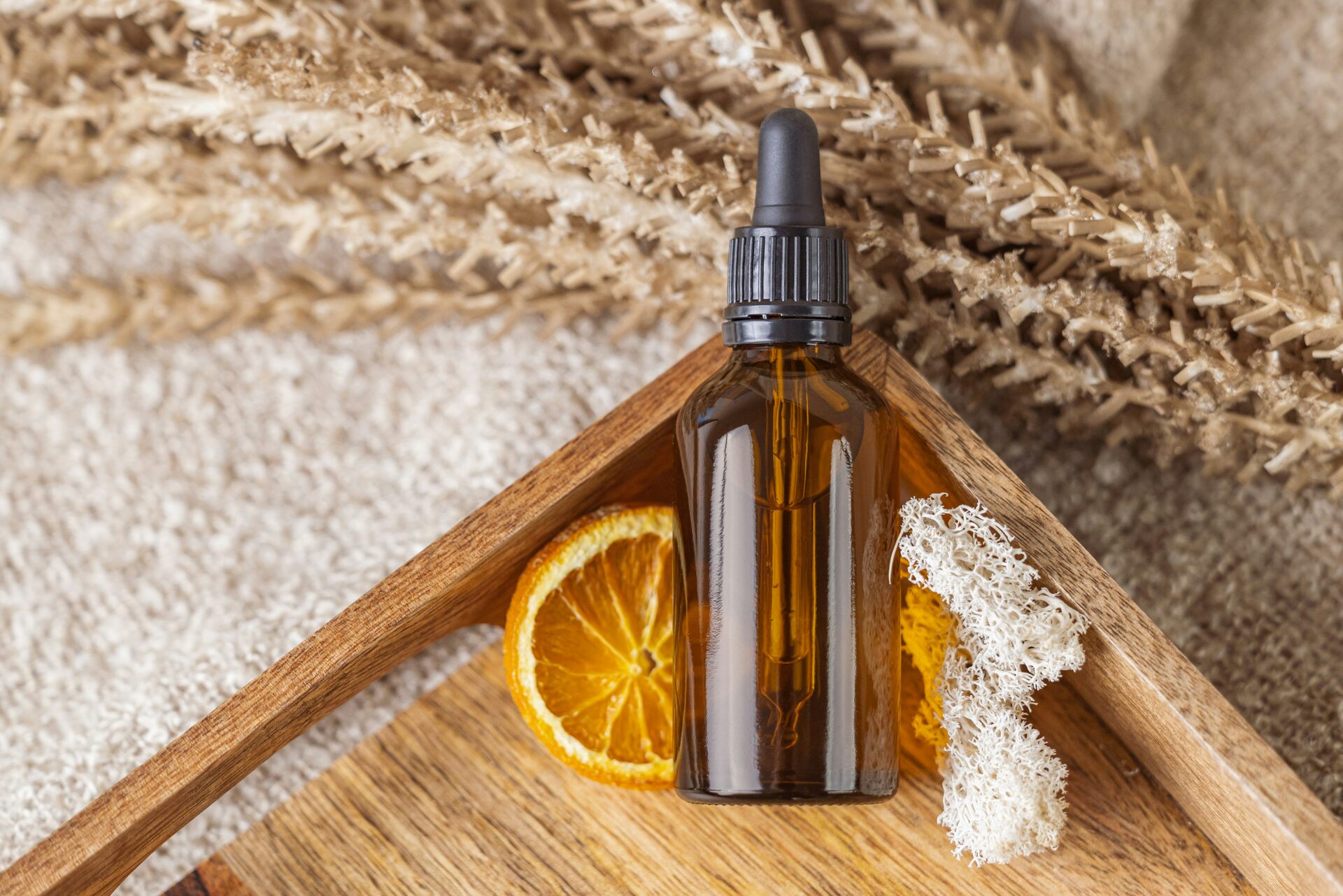 Baume Doré - amber dropper bottle on a wooden tray with dried orange and grasses